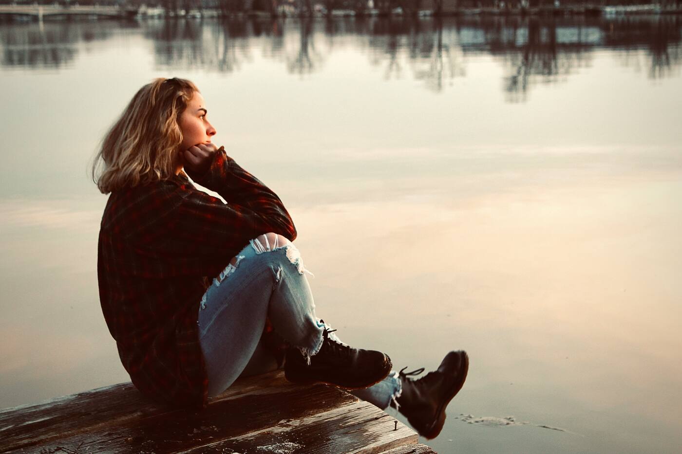 A person sitting at the water’s edge at dusk